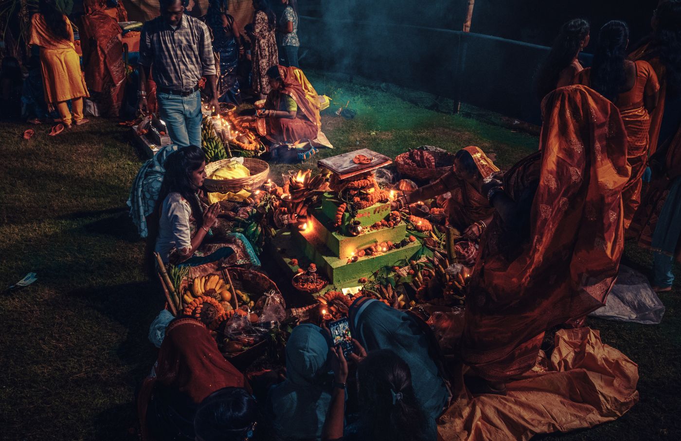 Families gathered around lamps and offerings at night